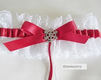 May include: White lace garter with a red satin bow and a rhinestone snowflake embellishment.