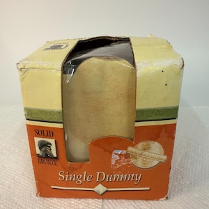 May include: A rectangular cardboard product box with a large cutout window. The box is colored in cream, green, and orange. Text on the front reads Solid Bronze, Single Dummy, and Lifetime Warranty. The box shows signs of wear and tear.