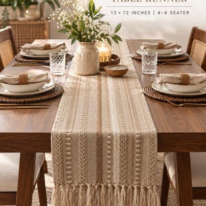 Op de afbeelding: Een premium katoenen tafelloper van 13 x 72 inch voor een tafel voor 4-6 personen. De loper heeft een beige en bruin gestreept patroon met verticale geweven texturen en een franjerand, weergegeven op een houten eettafel met tafelinstellingen.