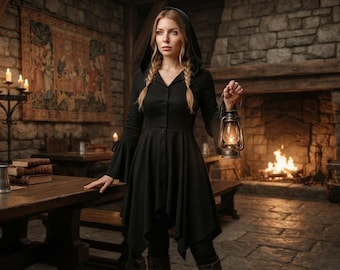 May include: A black hooded tunic featuring a button-down front, long sleeves with flared cuffs, and an asymmetrical hemline. The garment is worn with dark pants and is paired with a handheld metal lantern that emits a warm, glowing light.