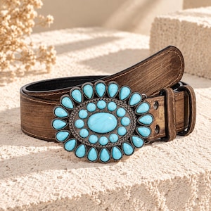 Pode incluir: Um cinto castanho com acabamento desgastado e uma fivela oval grande. A fivela é decorada com uma pedra turquesa oval central rodeada por dois anéis concêntricos de pedras turquesa mais pequenas em forma de gota em metal escuro.