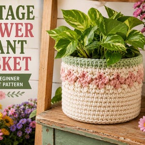 May include: A cylindrical crochet basket featuring a cream-coloured base, a band of pink floral motifs, and a sage green rim. The basket holds a green and yellow variegated pothos plant. Text on the left reads COTTAGE FLOWER PLANT BASKET.