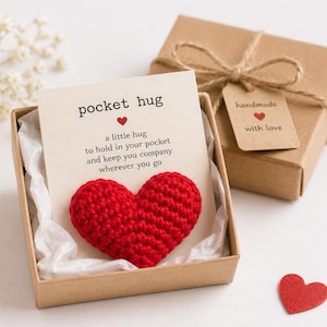 May include: A red crocheted heart attached to a card that reads pocket hug, a little hug to hold in your pocket and keep you company wherever you go, presented in a brown cardboard gift box with a tag that reads handmade with love.