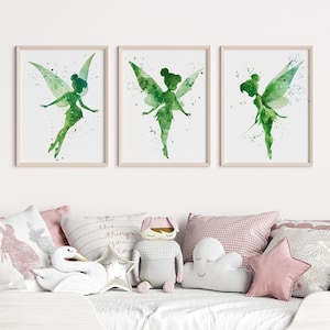 May include: Three framed wall art prints featuring watercolor illustrations of a fairy in shades of green. Each print displays a silhouette of a winged figure with paint splatter effects on a white background, housed in light wood frames.