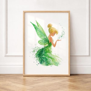 Puede incluir: Una lámina artística enmarcada con una ilustración en acuarela de un hada rubia con alas verdes translúcidas. El hada lleva un vestido verde que se disuelve en una estela de salpicaduras de pintura verde y destellos sobre un fondo blanco.
