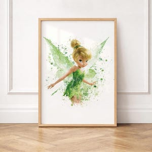 Puede incluir: Una lámina artística enmarcada con una ilustración en acuarela de un hada con el pelo rubio recogido en un moño, vistiendo un vestido verde con alas translúcidas. La obra utiliza salpicaduras y gotas de pintura verde sobre un fondo blanco.