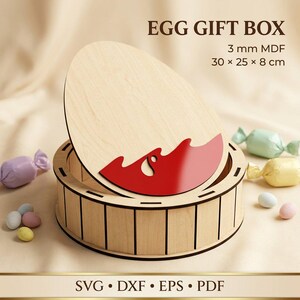May include: A round wooden egg gift box with a light wood finish and a removable egg-shaped lid featuring a red decorative accent. The text EGG GIFT BOX, 3 mm MDF, 30 x 25 x 8 cm, and SVG, DXF, EPS, PDF are printed on the image.