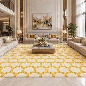 Peut inclure: Un grand tapis rectangulaire orné d'un motif répétitif en nid d'abeille jaune sur un fond crème. Le tapis recouvre le sol d'une pièce spacieuse, s'étendant du premier plan vers une table basse centrale et plusieurs canapés beiges.