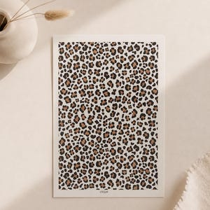 Op de afbeelding: Een rechthoekige print met een herhalend luipaardpatroon in tinten zwart, donkerbruin en beige op een crèmekleurige achtergrond. De print bevat de tekst MT321 in kleine zwarte letters gedrukt aan de onderste rand in het midden.
