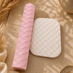Peut inclure: Un rouleau à pâtisserie cylindrique rose avec un motif géométrique en éventail en relief et une plaque d'argile blanche rectangulaire présentant une texture tressée assortie, conçus pour imprimer des motifs dans des matériaux souples.