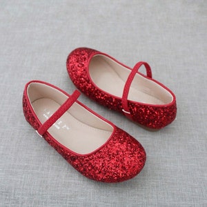 Puede incluir: Un par de bailarinas rojas de brillantina con una correa y cierre de hebilla. Los zapatos tienen un dise&ntilde;o sencillo y son perfectos para una ocasi&oacute;n especial.