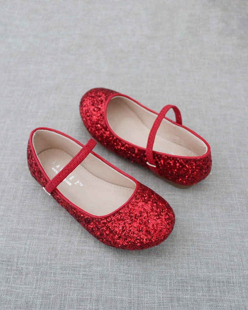 Puede incluir: Un par de bailarinas rojas de brillantina con una correa y cierre de hebilla. Los zapatos tienen un dise&ntilde;o sencillo y son perfectos para una ocasi&oacute;n especial.