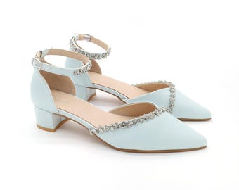 Puede incluir: Zapatos de tacón azul claro con una correa de tobillo y una fila de diamantes de imitación alrededor del borde superior.
