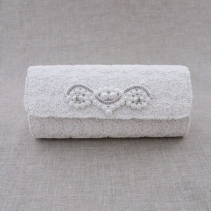May include: White lace clutch with a pearl and rhinestone embellishment.