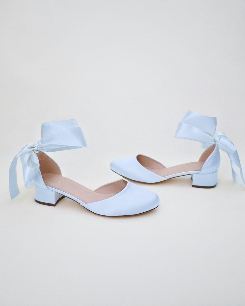 May include: A pair of light blue satin heeled shoes with a bow on the ankle strap.
