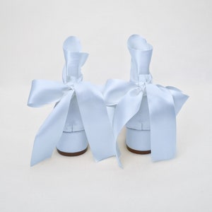 May include: A pair of light blue satin shoes with large bows tied around the ankles.