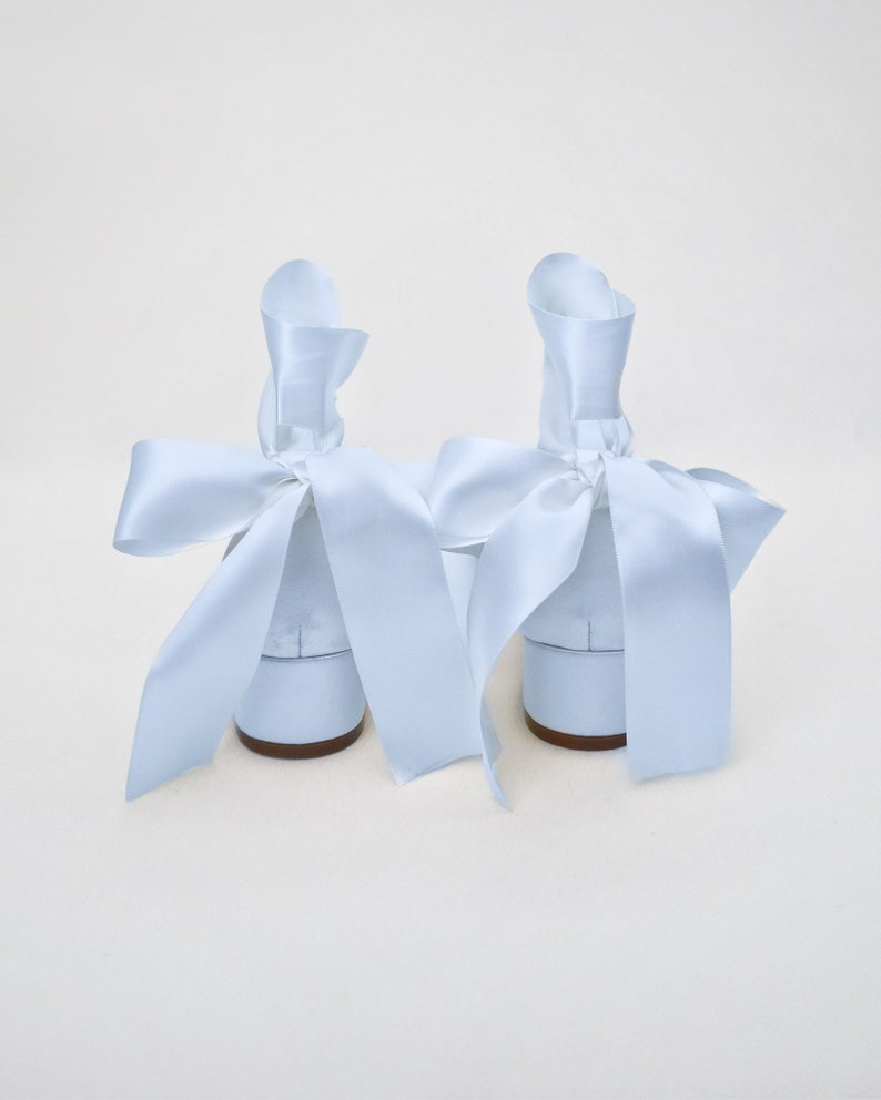 May include: A pair of light blue satin shoes with large bows tied around the ankles.