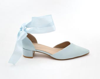 Puede incluir: Zapatos de tacón azul claro con una cinta a juego atada alrededor del tobillo.