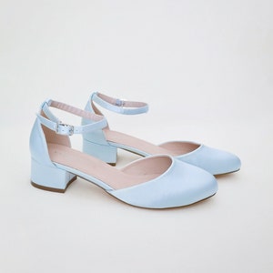 May include: A pair of light blue satin heeled shoes with ankle straps and a buckle closure.