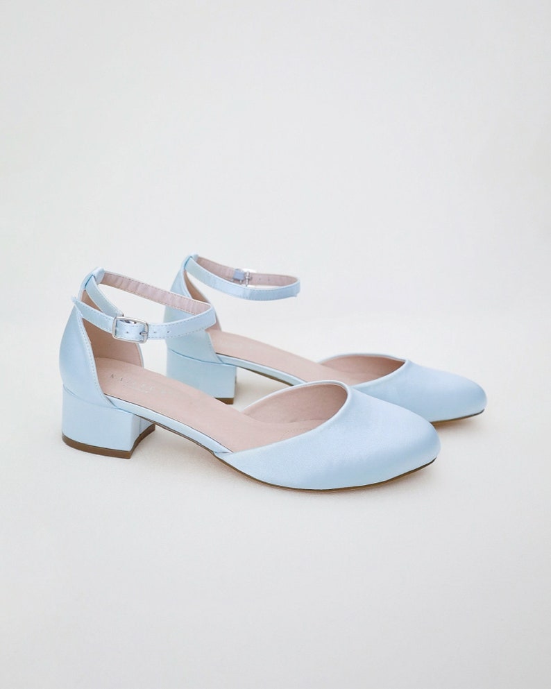 May include: A pair of light blue satin heeled shoes with ankle straps and a buckle closure.