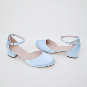 May include: A pair of light blue satin heeled shoes with ankle straps and a low block heel.