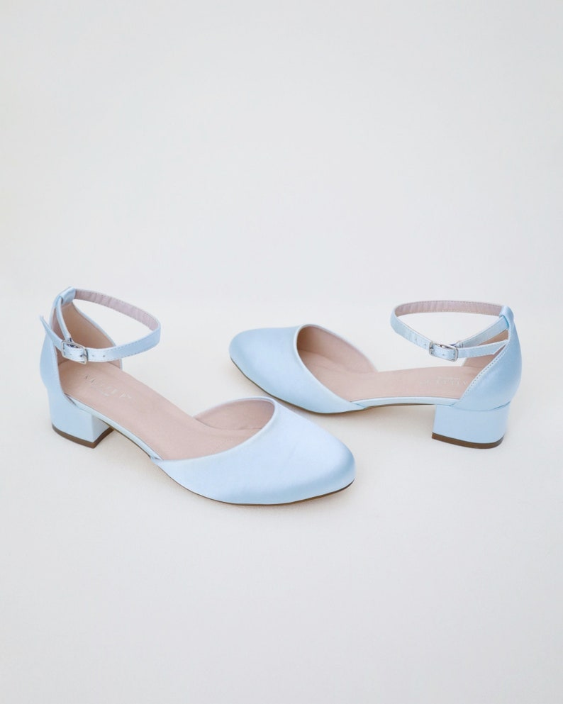 May include: A pair of light blue satin heeled shoes with ankle straps and a low block heel.