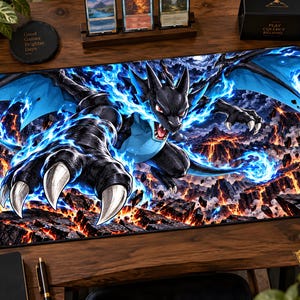 以下が含まれることがあります： 青い炎を纏った黒いドラゴンのような巨大な生き物が描かれた長方形のゲーミングプレイマット。その生き物は鋭い白い爪を持ち、溶岩の裂け目が光る暗い岩場の風景の上に配置されている。