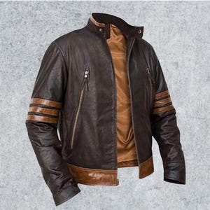 Può includere: Una giacca in pelle marrone scuro con colletto alla coreana, chiusura frontale con zip e fodera interna color cuoio. Le maniche sono decorate con tre strisce orizzontali color cuoio e l'orlo inferiore è rifinito con un'ampia fascia in pelle.