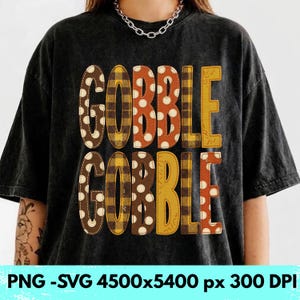 May include: A black acid-wash t-shirt featuring the text GOBBLE GOBBLE printed in large, blocky letters. Each letter displays a different pattern, including brown and white polka dots, yellow and black plaid, and solid orange and yellow colors.