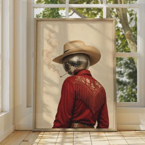 May include: A framed wall art print depicting a figure wearing a tan cowboy hat and a red long-sleeved shirt with fringe and floral embroidery. The figure has a reflective disco ball for a head and is holding a lit cigarette with visible smoke.