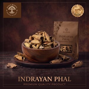 Pode incluir: Uma tigela de madeira cheia de pedaços de fruta seca Indrayan Phal, acompanhada por um saco de papel castanho com o rótulo Jeeva Roots Indrayan Phal Premium Herbal Remedy. A embalagem apresenta um selo 100% Natural e o texto Indrayan Phal Premium Quality Product.