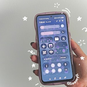 Könnte beinhalten: Ein Smartphone mit einer durchscheinenden violetten Hülle mit gewelltem Rand, das eine benutzerdefinierte violette Benutzeroberfläche mit verschiedenen runden Symbolen, einer Digitaluhr mit 7:30:42 und handgezeichneten weißen Sternen und Wirbeln zeigt.