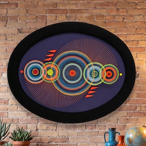 May include: An oval wall art piece featuring a dark purple background with a series of concentric circular patterns in shades of blue, orange, yellow, and red. The design includes radiating lines and small orange triangular accents in a black frame.