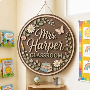 Pode incluir: Uma placa circular de madeira para sala de aula com o texto Mrs. Harper CLASSROOM em letras brancas em relevo. A placa &eacute; decorada com motivos florais 3D, uma borboleta, uma joaninha, um l&aacute;pis e uma pilha de tr&ecirc;s livros em tons pastel.