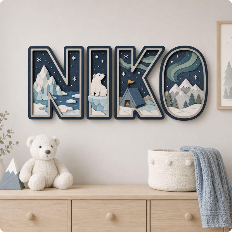 May include: A wall-mounted decorative sign spelling the name NIKO in large, dark blue block letters. Each letter features a layered, 3D-style winter scene with white mountains, a polar bear, a blue tent, and green aurora borealis against a dark sky.