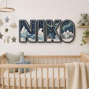 May include: A wall-mounted decorative sign spelling the name NIKO in large, layered block letters. Each letter features a deep blue background with a 3D arctic scene including white mountains, a polar bear, a small tent, and green aurora lights.