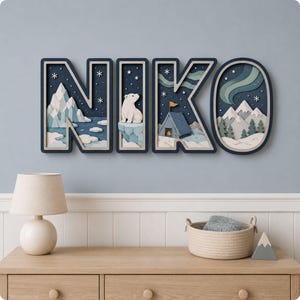 May include: A multi-layered wall art piece spelling the name NIKO in dark blue block letters. Each letter features a 3D arctic scene with a polar bear, snowy mountains, pine trees, a small tent with a flag, and a green aurora borealis in the sky.