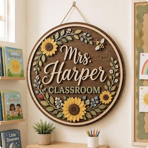 Pode incluir: Uma placa de parede circular de madeira com o texto Mrs. Harper CLASSROOM em letras brancas. A placa &eacute; decorada com uma guirlanda de girass&oacute;is amarelos, folhas verdes, pequenas flores azuis, uma joaninha e uma abelha com voo.