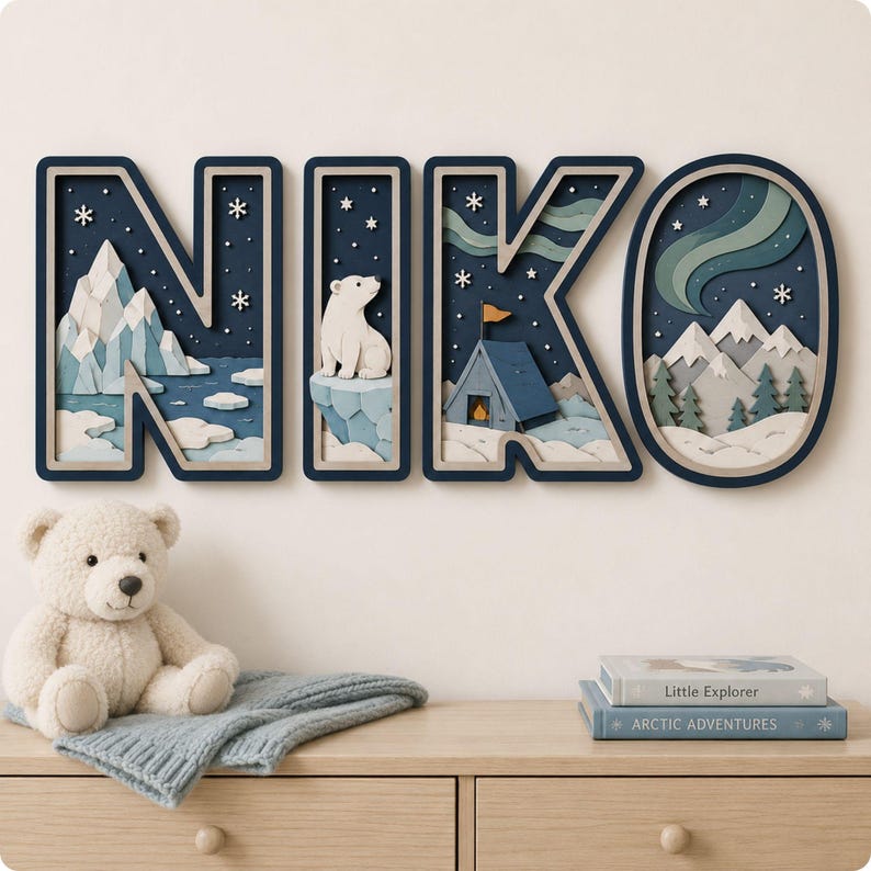 May include: A set of four layered wooden wall letters spelling NIKO, featuring a dark blue frame and intricate arctic scenes including a polar bear, snow-capped mountains, a tent, and northern lights against a starry night sky with white snowflakes.