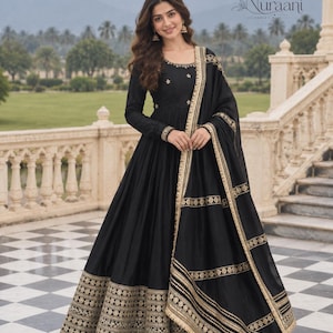 Könnte beinhalten: Ein bodenlanges schwarzes Kleid mit langen Ärmeln und Rundhalsausschnitt, verziert mit goldener Stickerei an Oberteil, Ärmelbündchen und Saum. Ein passender schwarzer Schal mit goldenen Streifenmustern und Blumenmotiven liegt über den Schultern.