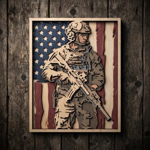 May include: A multi-layered wooden wall art piece featuring a soldier in tactical gear holding a rifle, positioned in front of a stylized American flag with blue, white, and red sections. The design uses depth and wood tones to create a relief effect.