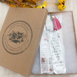 May include: A silver bookmark with a pink tassel. The bookmark has a floral design and the text "A truly amazing teacher is hard to find, difficult to part with, & impossible to forget."