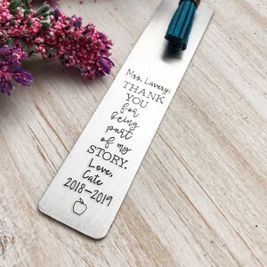 May include: A silver bookmark with a teal tassel. The bookmark has the text "Mrs. Lavery, THANK YOU for being part of my STORY. Love, Cate 2018-2019" engraved on it.