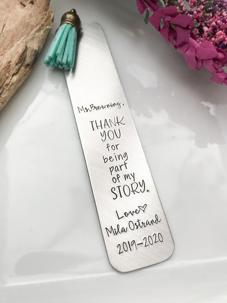 May include: A silver bookmark with a turquoise tassel. The bookmark has the text "Ms. Browning, THANK YOU for being part of my STORY. Love Mila Ostrand 2019-2020" engraved on it.