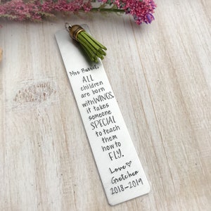 May include: A silver bookmark with a green tassel. The bookmark has the text "Mrs. Barret, ALL children are born with WINGS. It takes someone SPECIAL to teach them how to FLY. Love Gretchen 2018-2019" engraved on it.