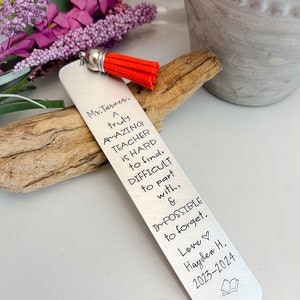 May include: Silver bookmark with a red tassel, featuring the text "Mr. Turner, A truly AMAZING TEACHER is HARD to find, DIFFICULT to part with, & IMPOSSIBLE to forget. Love Hayden H. 2023-2024"