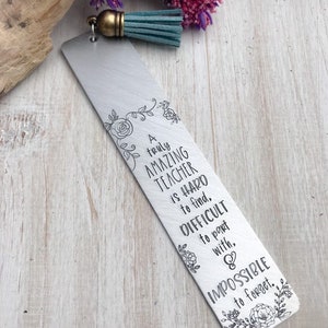 Op de afbeelding: Een zilveren bladwijzer met een turquoise kwast. De bladwijzer heeft een bloemmotief en de tekst "A truly AMAZING TEACHER is HARD to find, DIFFICULT to part with, & IMPOSSIBLE to forget."