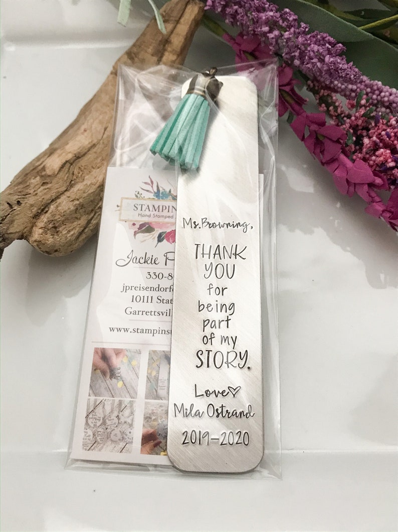 May include: A silver bookmark with a turquoise tassel. The bookmark has the text "Ms. Browning, THANK YOU for being part of my STORY. Love Mila Ostrand 2019-2020" engraved on it.