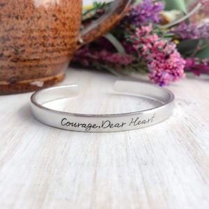 Pode incluir: Pulseira de bracelete de prata com a inscrição "Courage, Dear Heart".