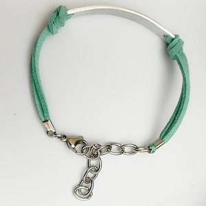May include: A green suede bracelet with a silver metal band and a silver clasp.